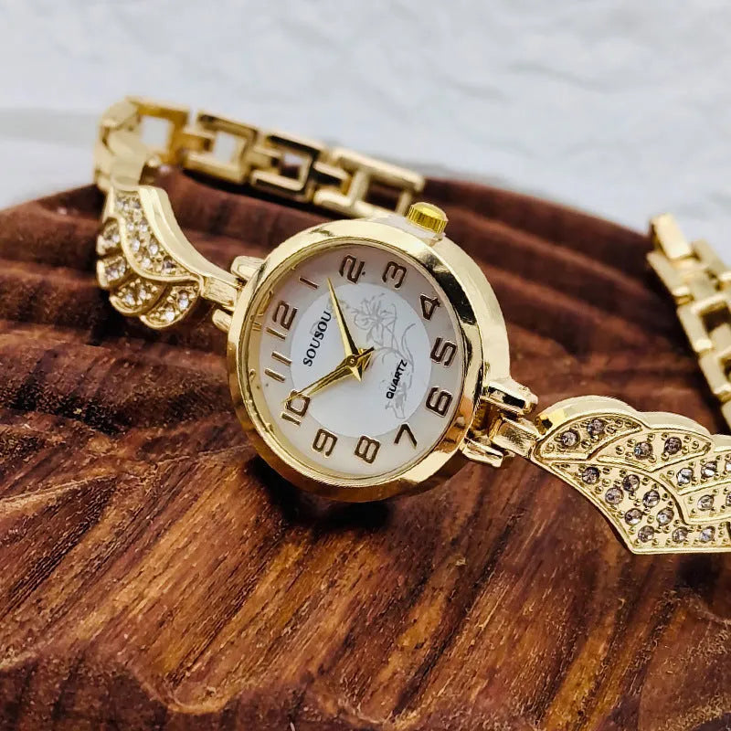A stainless steel women's watch with a round dial on a metal strap, showing a gold-coloured face.