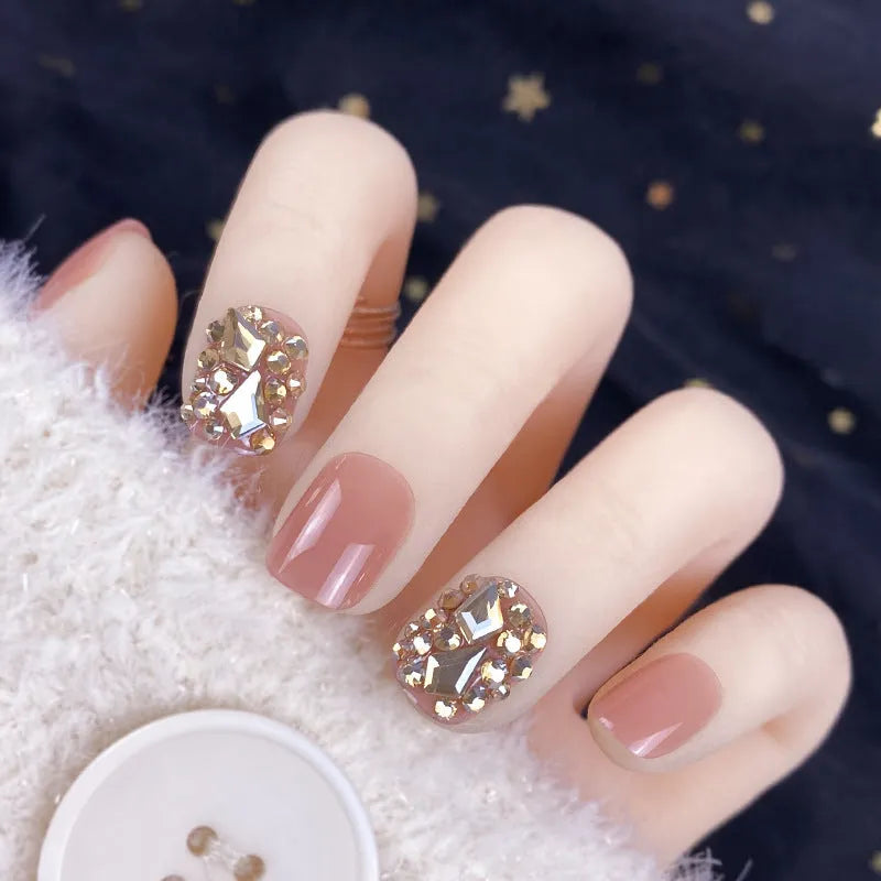 Champagne gold full diamond manicure patches laid out on a surface, showing the sequin finish and adhesive backing