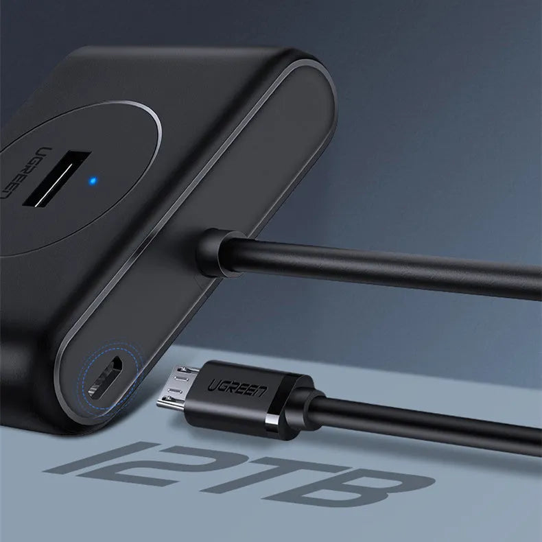 Deep black USB splitter with four ports, Micro USB power port, and indicator light on a desk