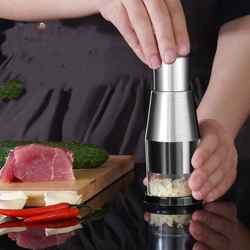 Black manual garlic press and onion chopper with stainless steel blades on a kitchen counter.