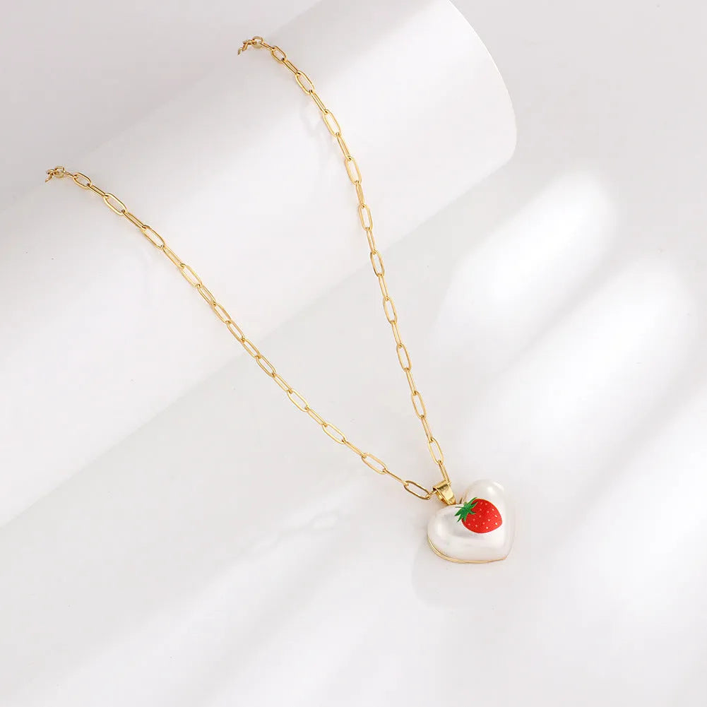 Geometric heart-shaped necklace with a detailed strawberry charm pendant on an adjustable chain.