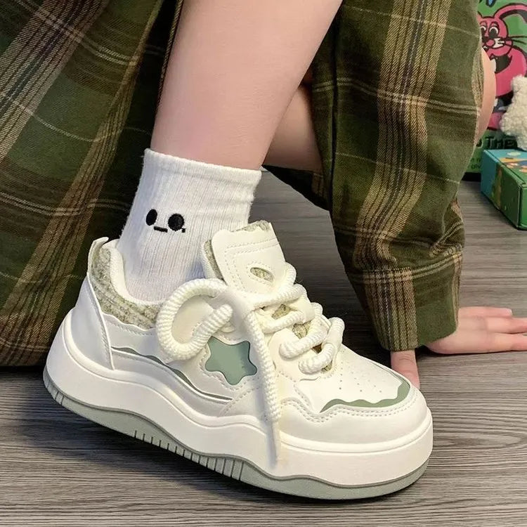 Women's green patent leather-look platform sneaker with round toe and white lace-up front, on a white background.