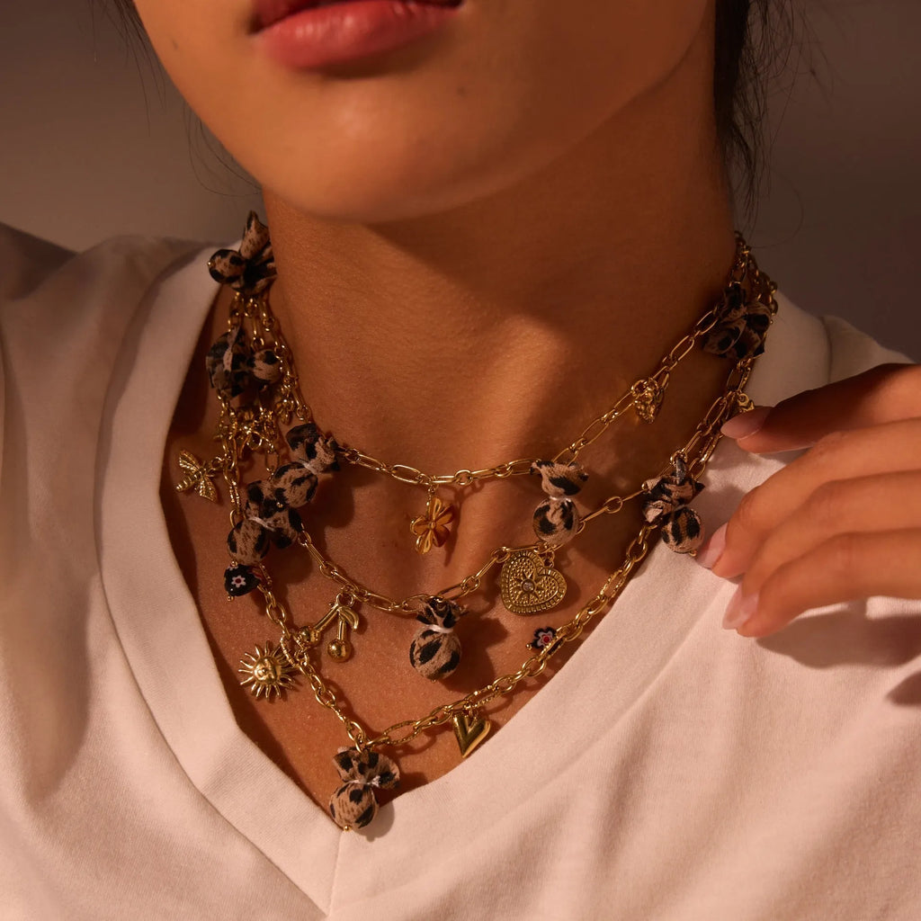 Stainless steel necklace with a geometric leopard pendant and heart and flower accents on an adjustable chain.