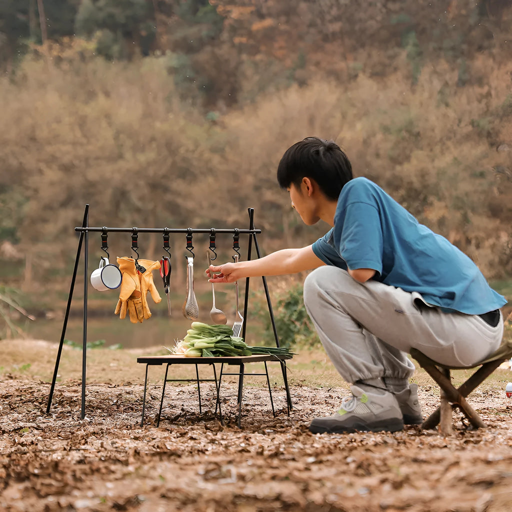 Aluminium alloy portable folding clothes drying rack with triangular frame and top tray, set up outdoors.