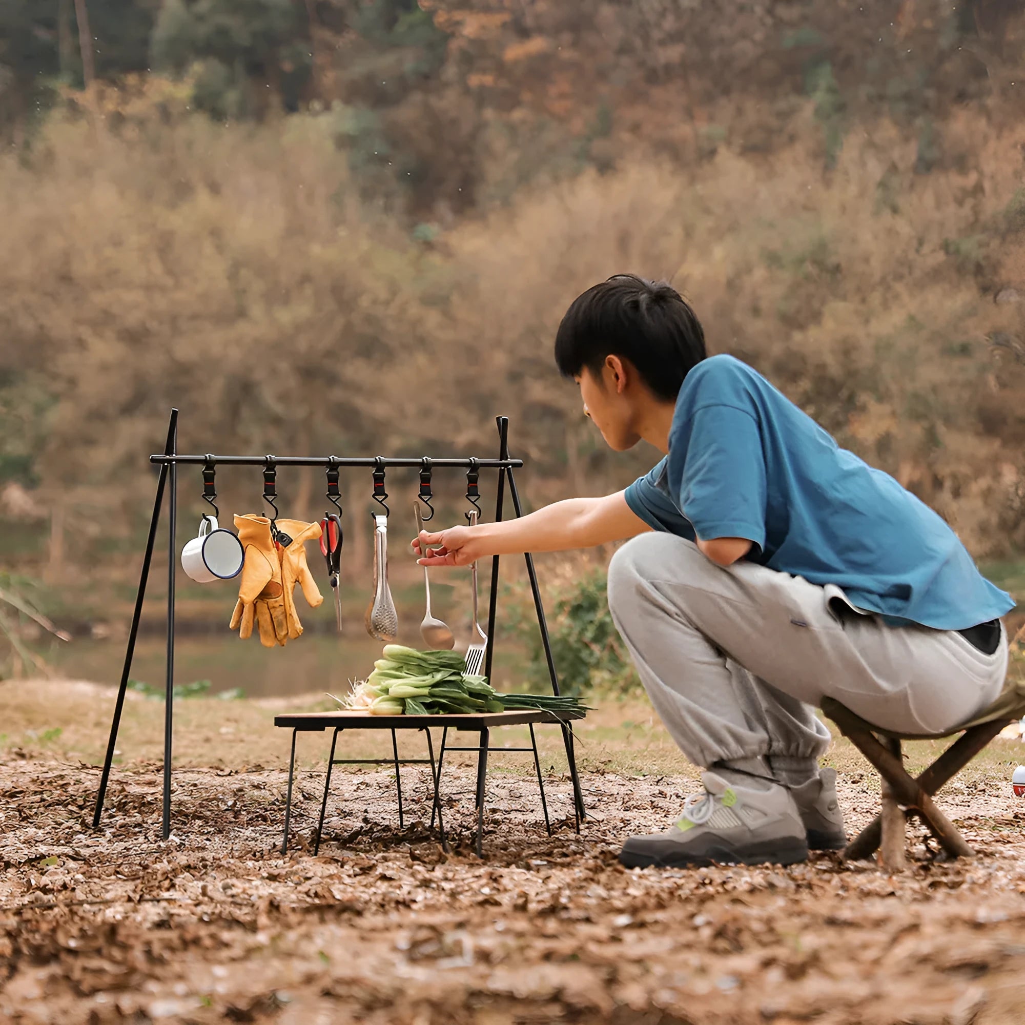 Aluminium alloy portable folding clothes drying rack with triangular frame and top tray, set up outdoors.