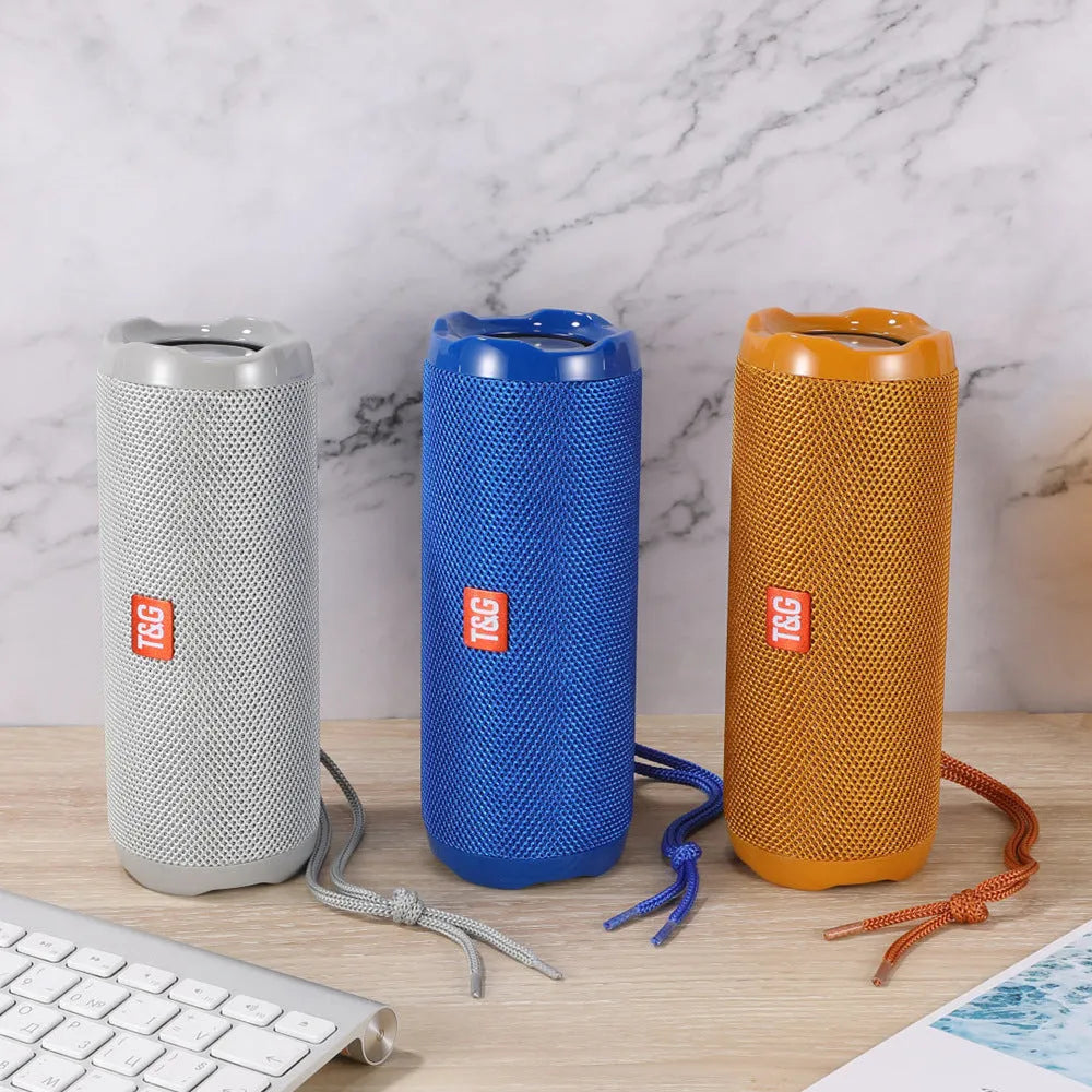 Fabric-covered portable Bluetooth speaker with a visible card slot in colours blue, black, red, gold, silver grey, and camouflage.