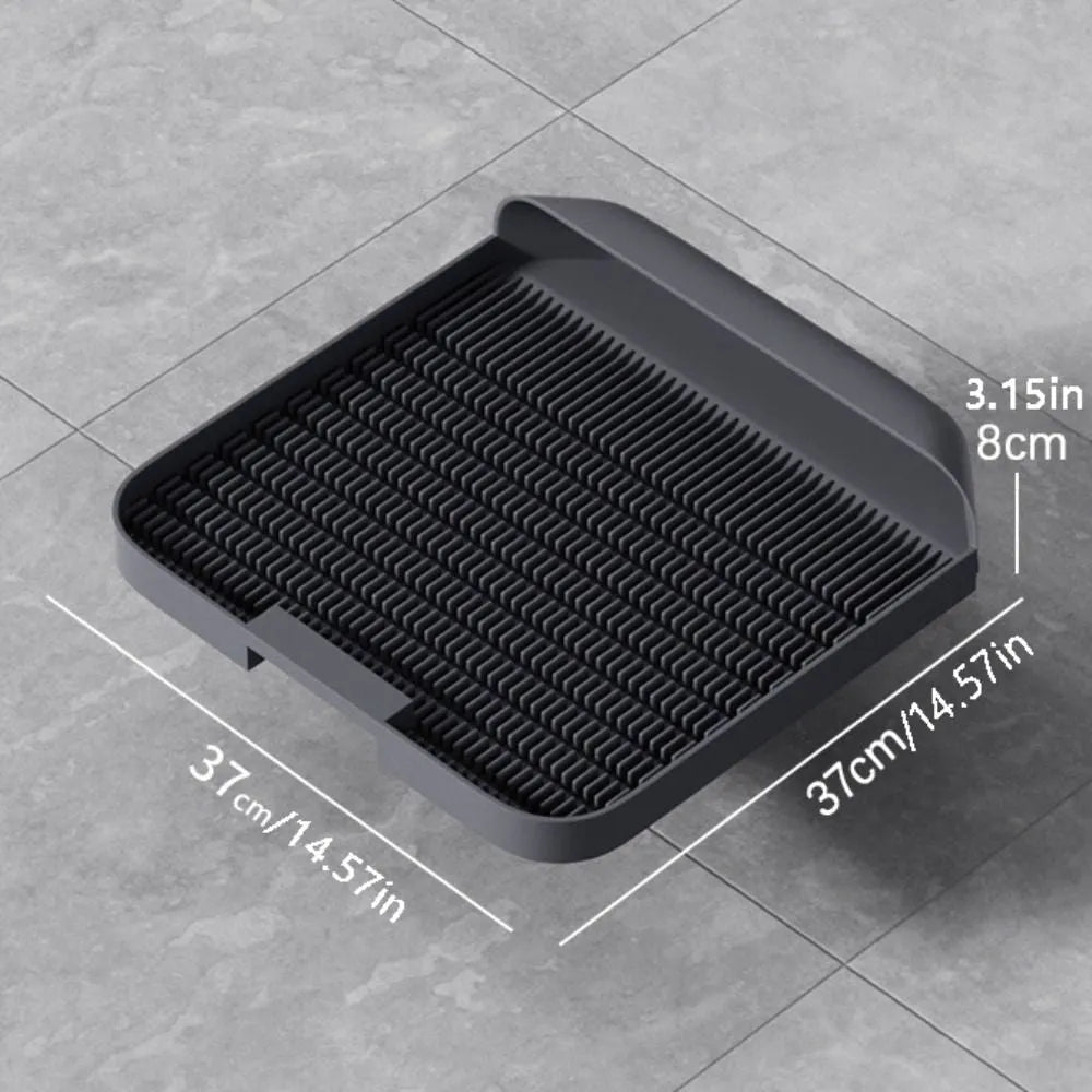 Large black cat litter pedal mat with slanted design next to a litter box.