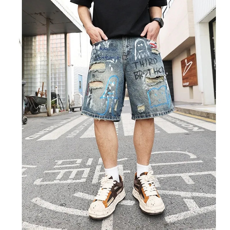 Blue men's ripped denim shorts with graffiti design and straight leg.