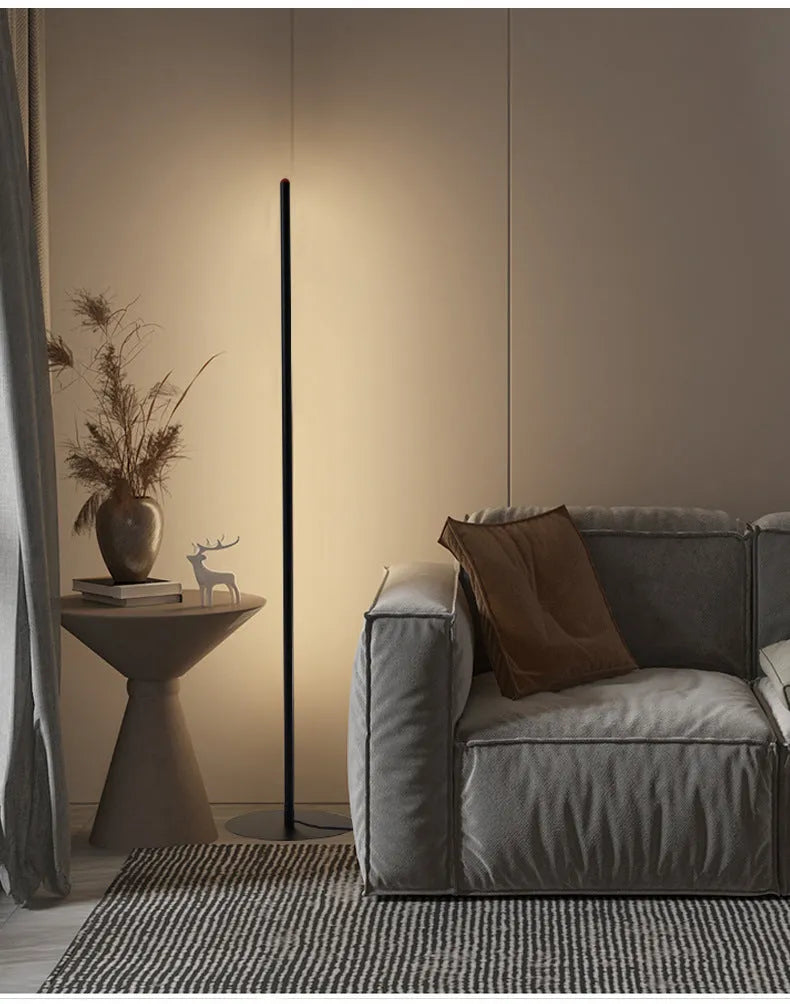 Slender vertical aluminium alloy LED floor lamp in a modern design next to a sofa.