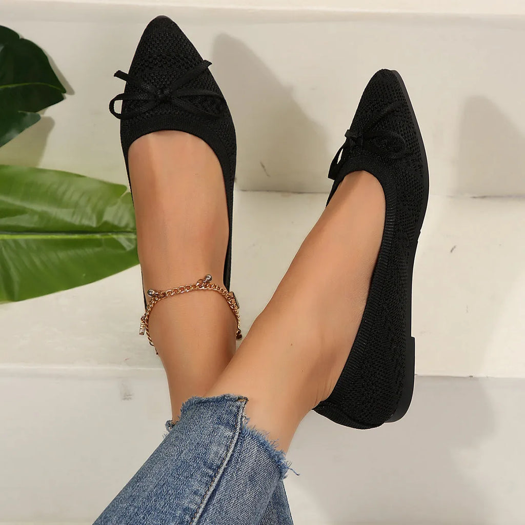 Women's blue knitted flat loafer with bow detail on pointed toe, showing rubber sole