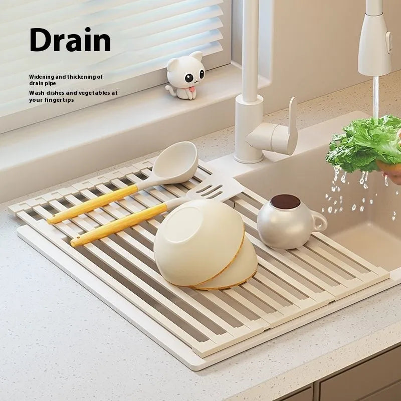 Milky White foldable stainless steel kitchen draining rack shown beside a sink, demonstrating its tri-fold mechanism.