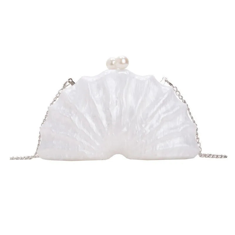 Acrylic shell-shaped clutch bag in champagne with silver chain on white background