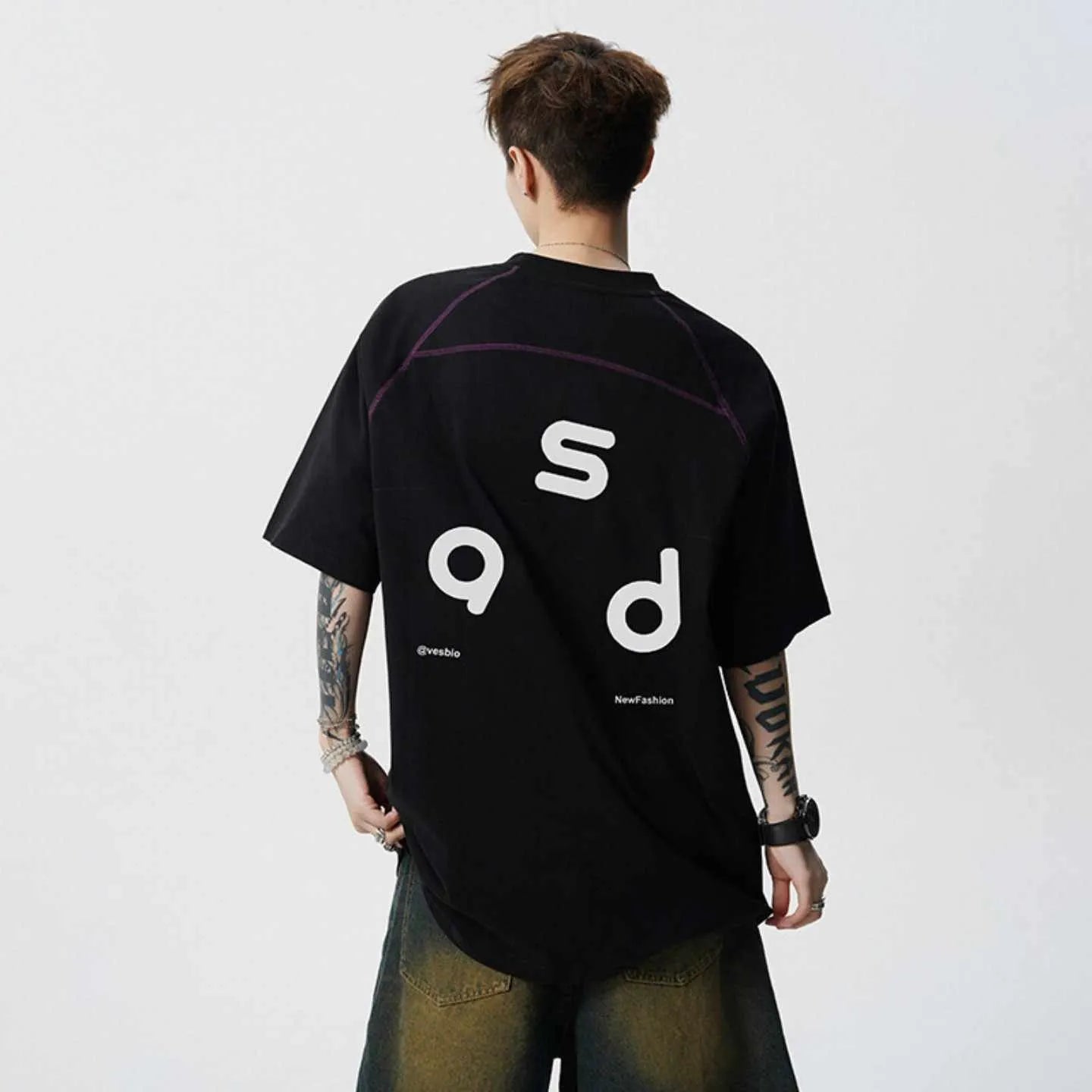 Man wearing a loose-fitting black cotton T-shirt with a white letter print on the chest.