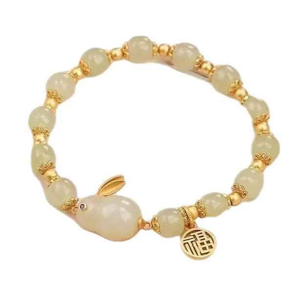 Green jade hare bracelet on wrist showing fu character and lily design details.