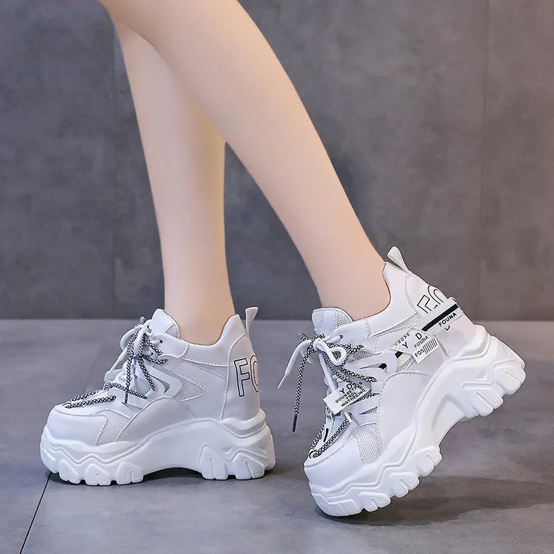 Women's white and black platform sports shoes with cross strap and rubber sole.