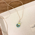 Women's necklace with a colourful skirt joker pendant on a long, braided cotton and linen chain.