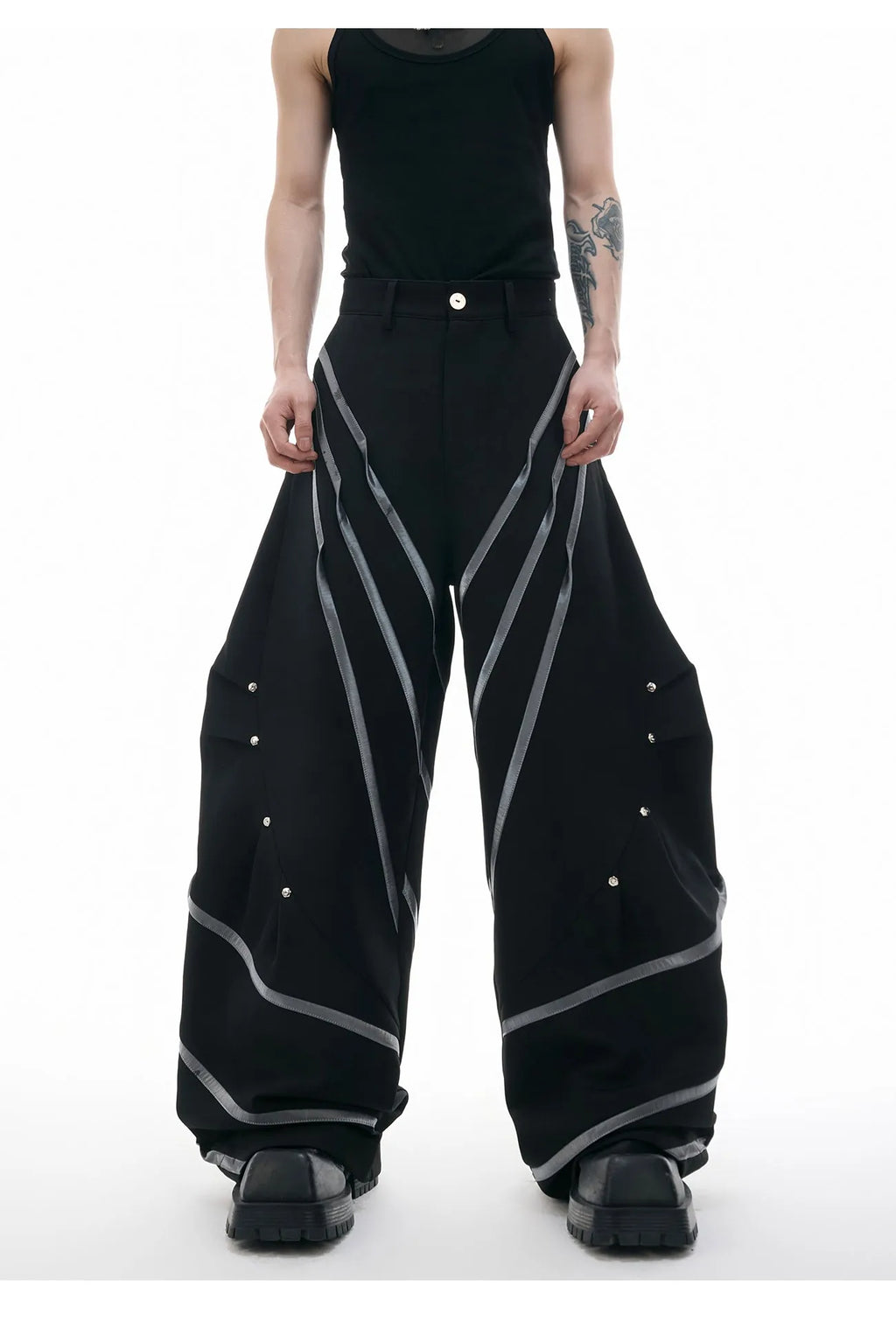 Men's black trousers with metal rivet pleats and a three-dimensional tailored cut.