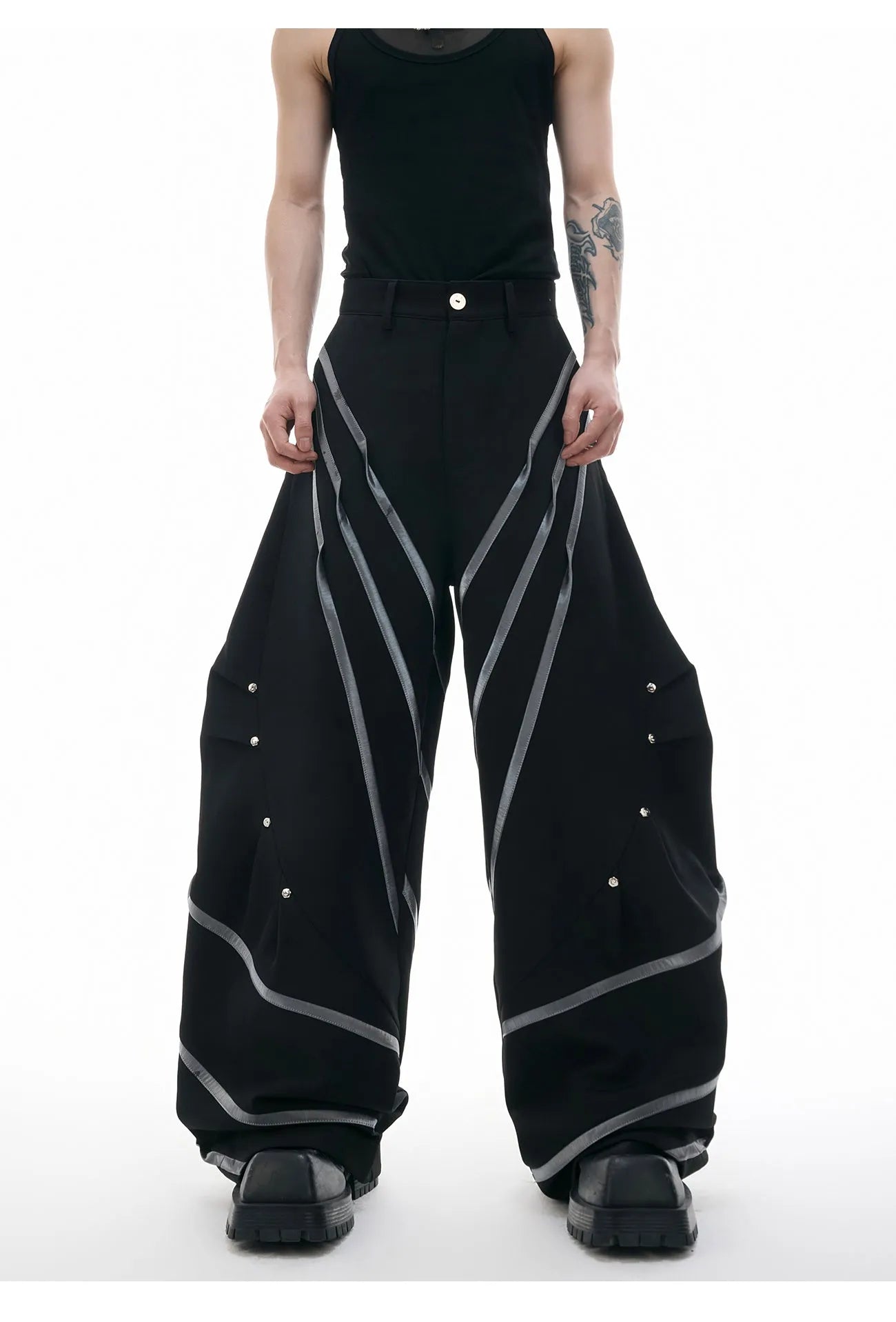 Men's black trousers with metal rivet pleats and a three-dimensional tailored cut.