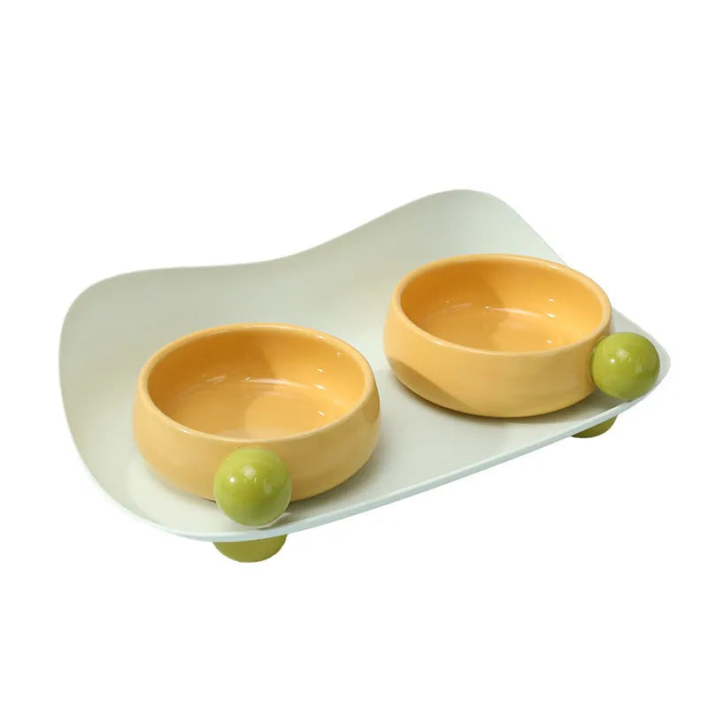 Pink elevated ceramic double bowl set for cat food and water on a non-slip base.