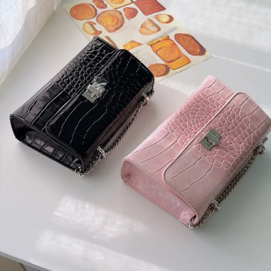 Black polyester fibre crossbody bag with chain strap, bow tie accent, and small square shape for everyday commuting
