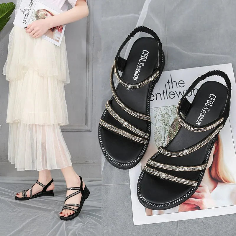 Women's silver flat sandals with rhinestone embellishment and an elastic strap on a rubber sole.