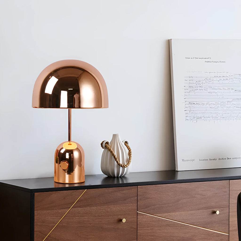Mushroom-shaped table lamp with metal base in rose gold finish on wooden surface