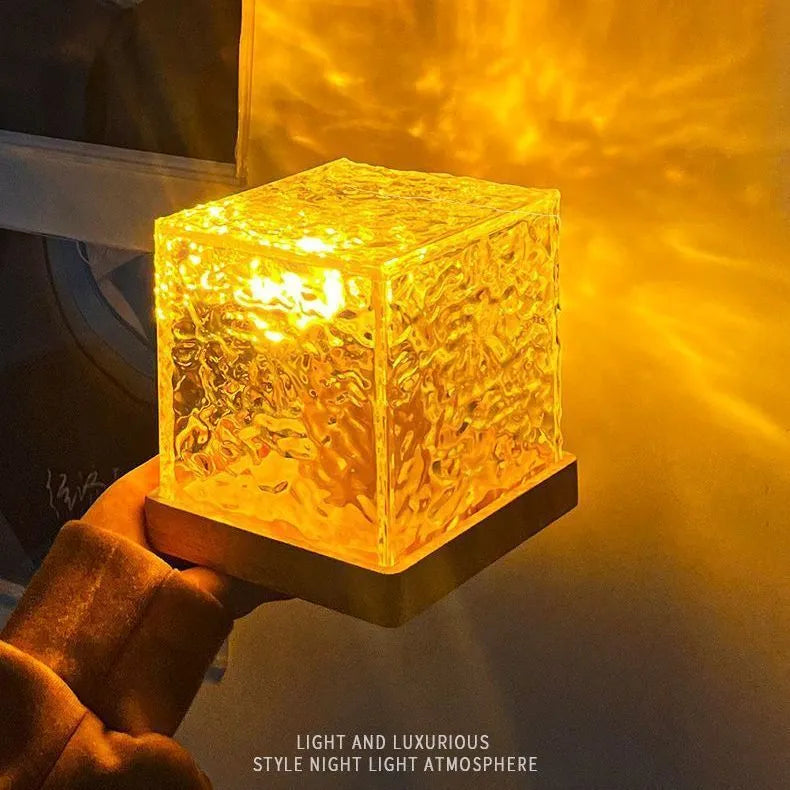 Modern geometric crystal table lamp projecting blue water ripple light pattern on a wall.