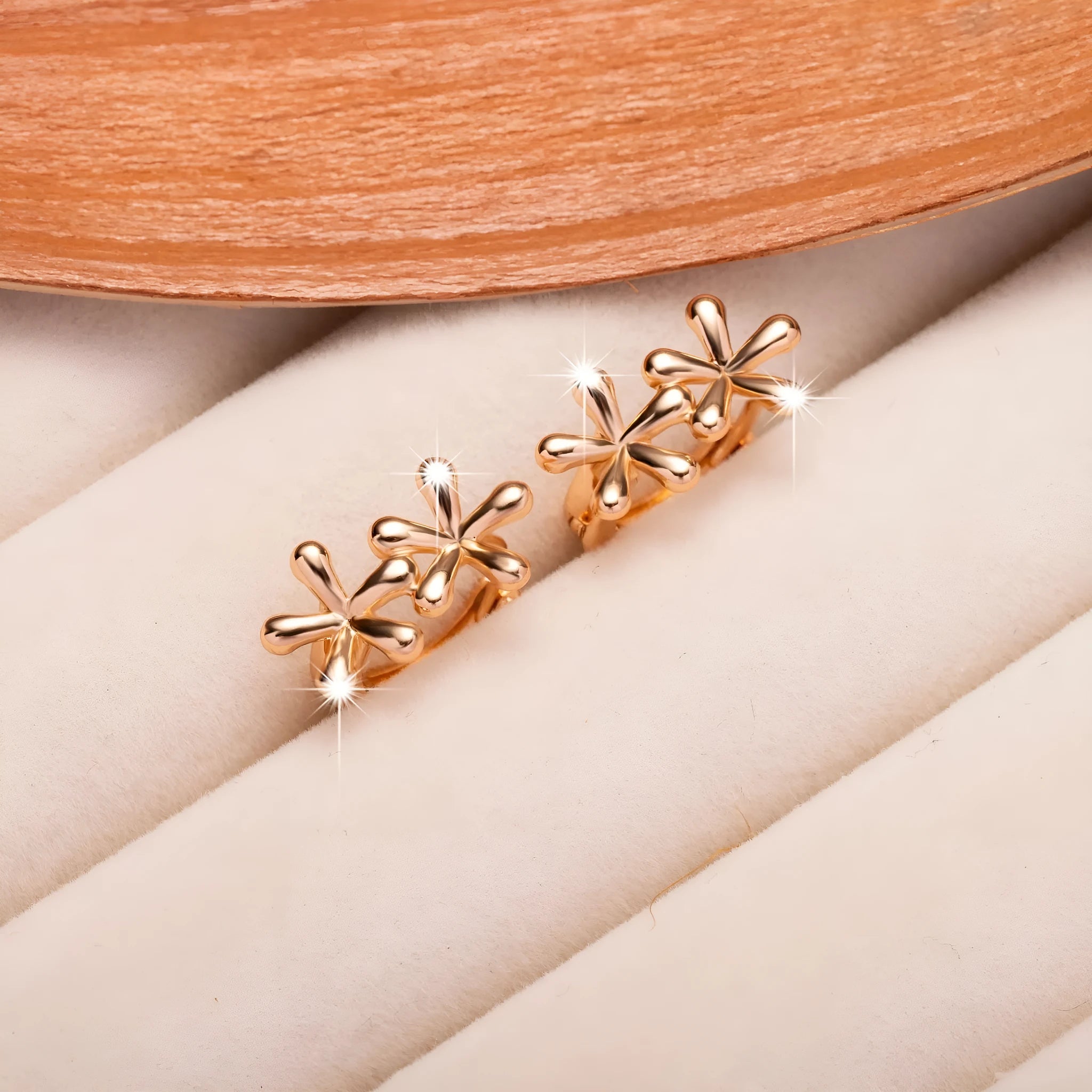 Rose gold circular earrings with a raised waterdrop floral design on a white background.