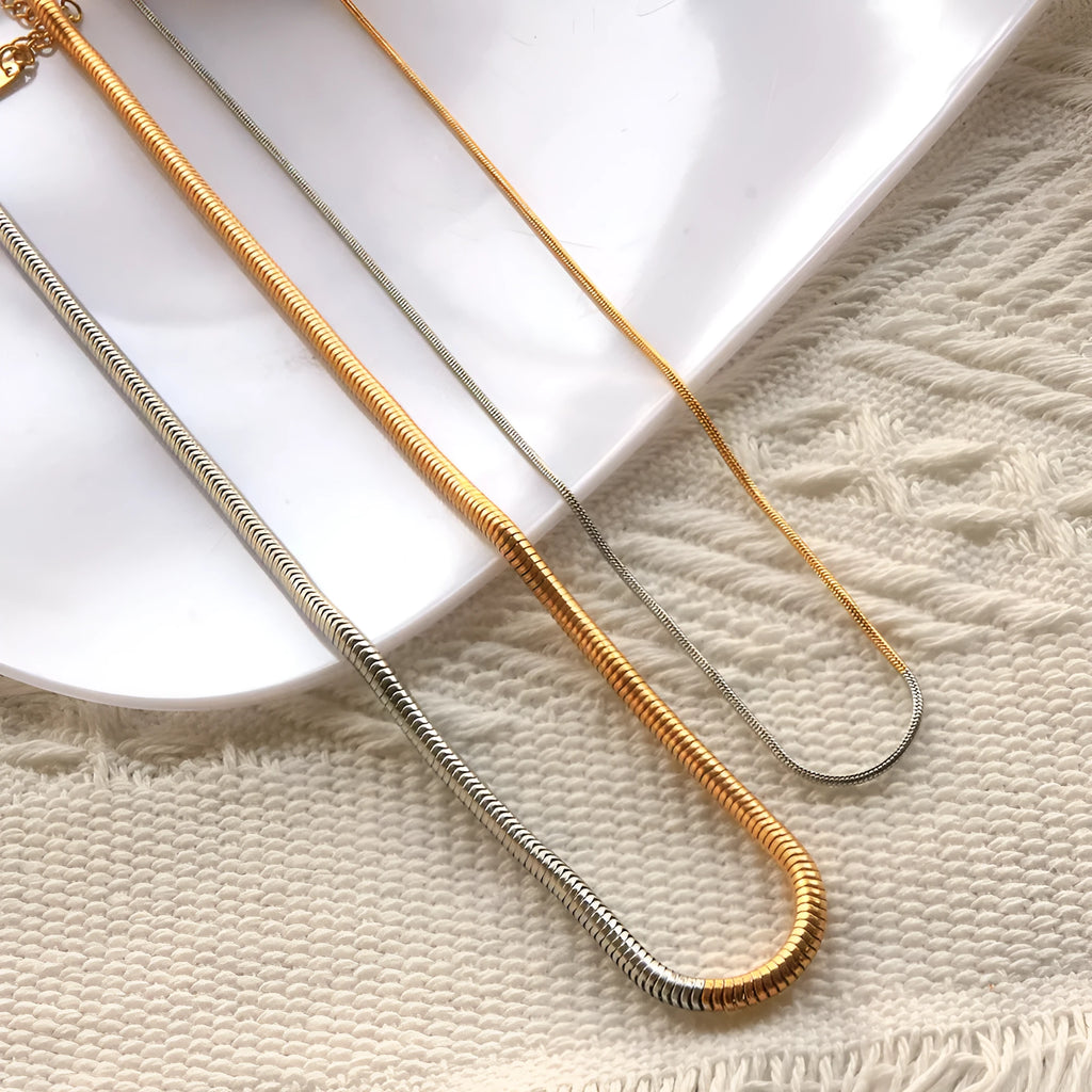 Gold tone stainless steel snake bone chain necklace with geometric line details, shown on a plain background.