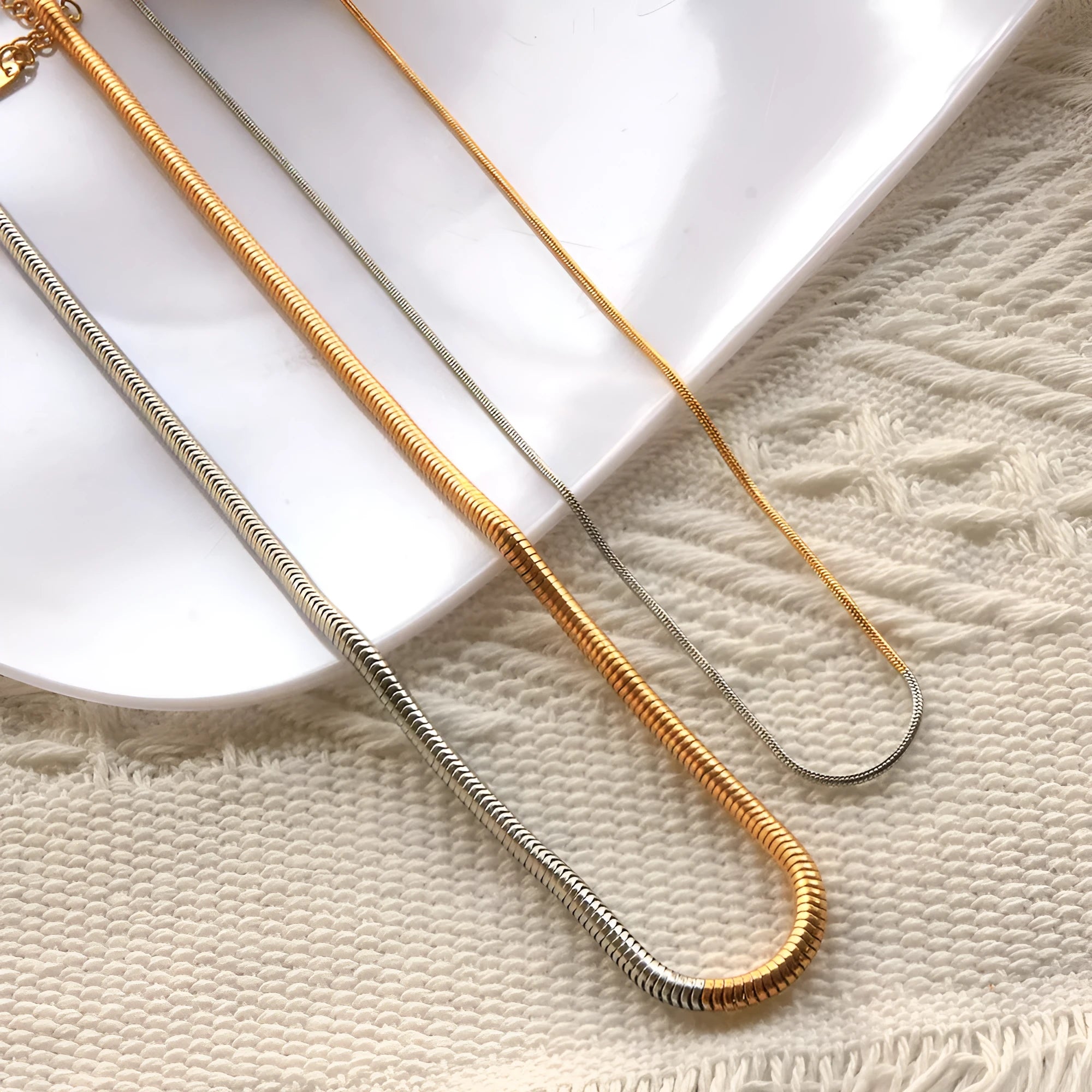 Gold tone stainless steel snake bone chain necklace with geometric line details, shown on a plain background.