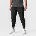 Men's solid colour polyester jogger pants in black, mid-waist micro-elasticity sports trousers for autumn leisure.