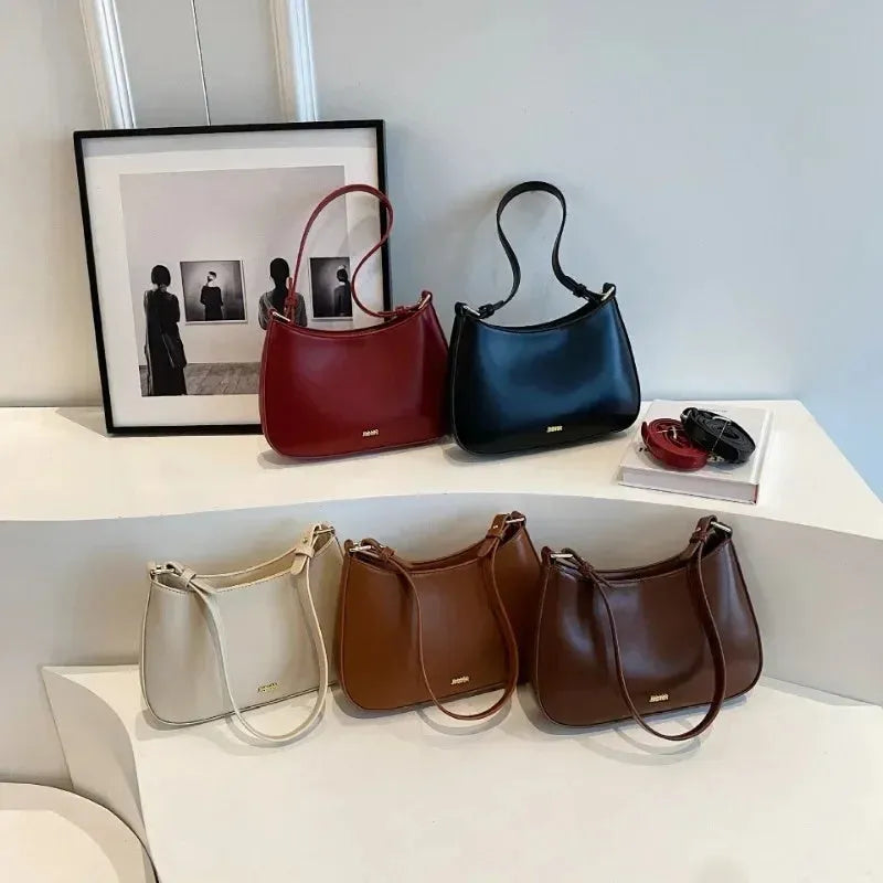 Red underarm shoulder bag in textured faux leather with adjustable strap for crossbody or sling wear