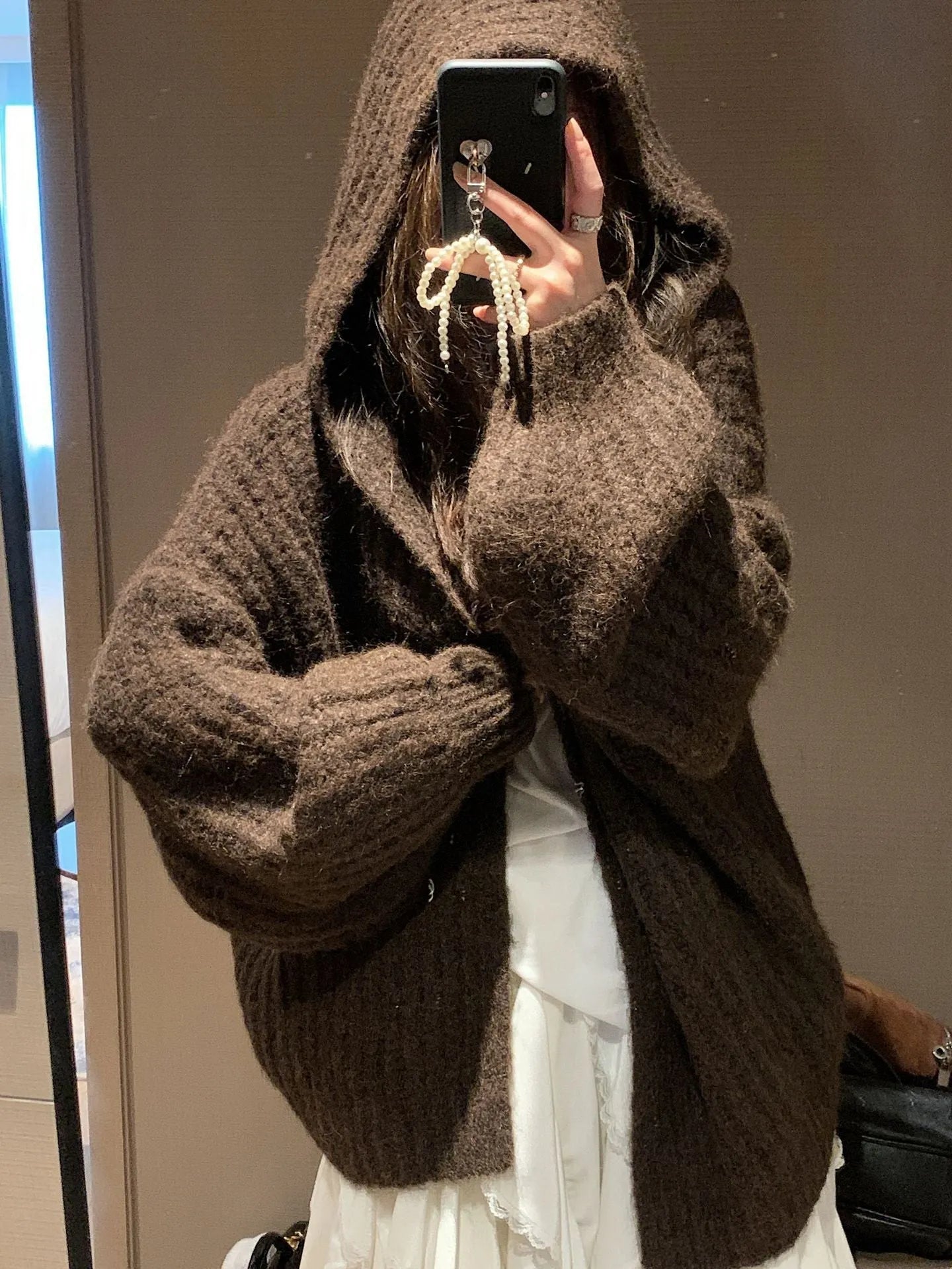 Woman wearing a thick dark grey hooded zip-up cardigan, loose fit.