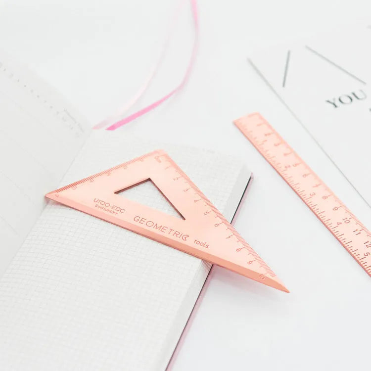 Rose gold and yellow stainless steel ruler set with protractor, triangle, and straightedge in transparent pocket