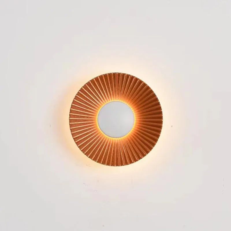 Round aluminium wall lamp in an outer white and inner gold colour combination, mounted on a wall.