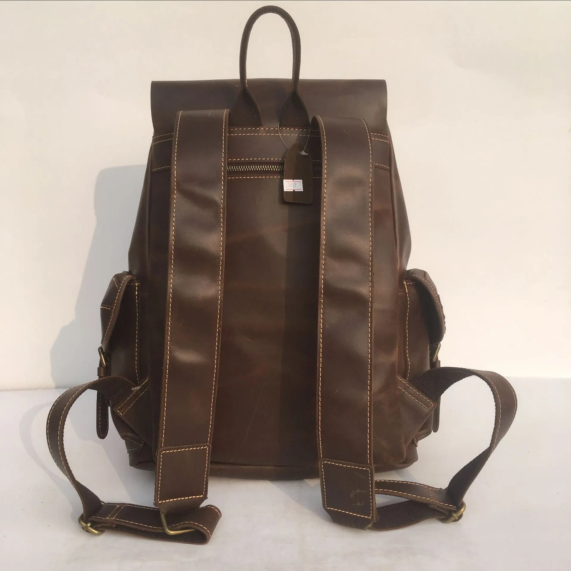 Brown leather men's backpack with shoulder straps showing cowhide leather texture