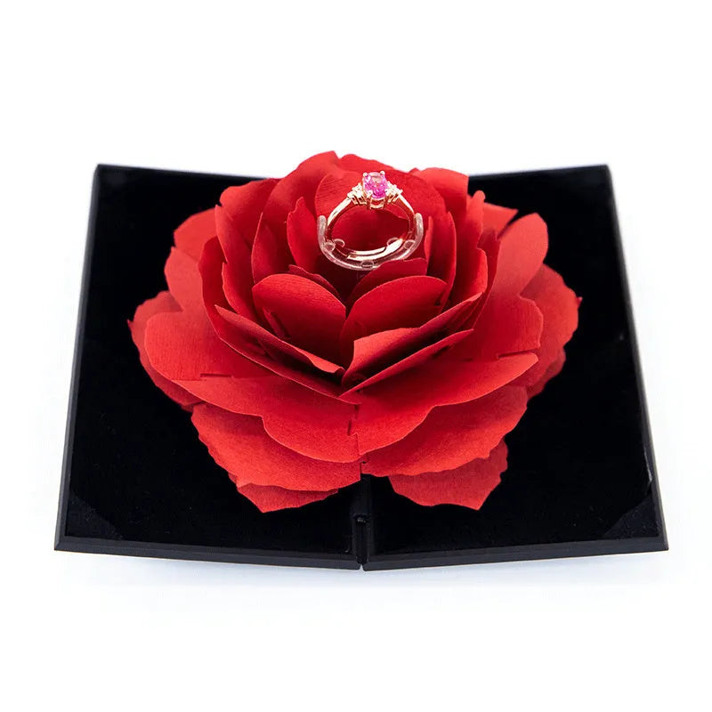 Red rotating 3D heart-shaped plastic ring box with a rose, open to show ring placement.