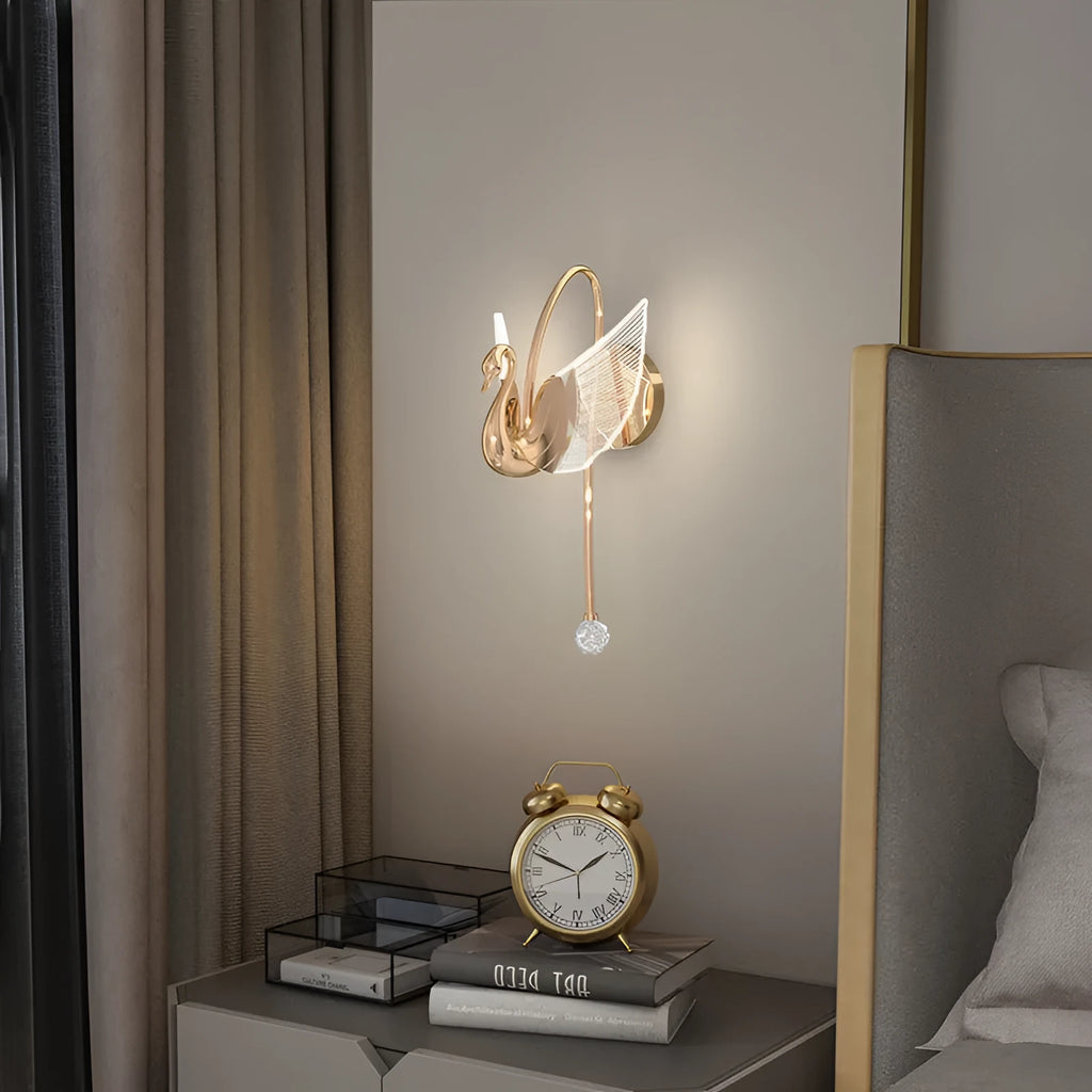 Gold modern swan-shaped bedside wall lamp with an acrylic shade mounted on a wall.