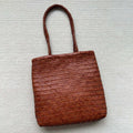 Brown vintage woven leather tote bag with a three-dimensional front pocket.