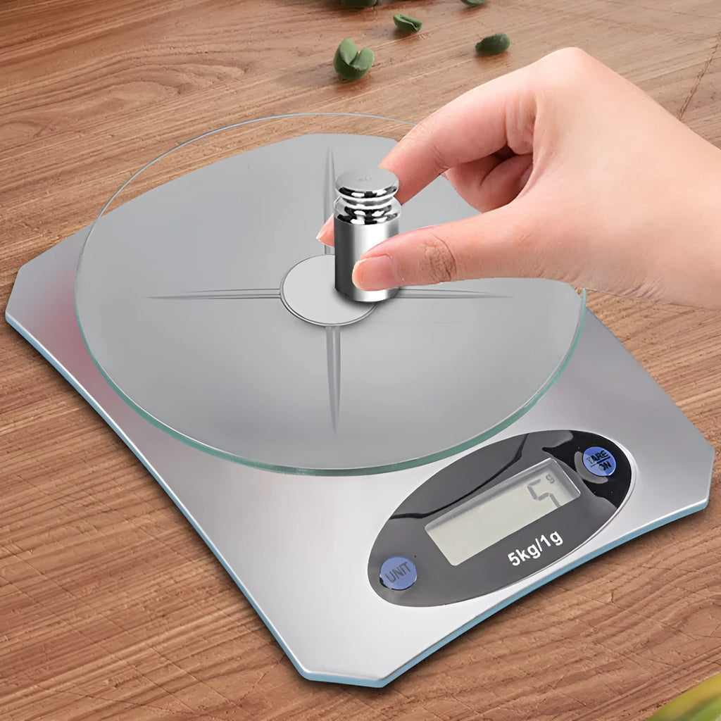 Simple mini kitchen electronic scale in silver white colour on a flat surface, showing weighing display.