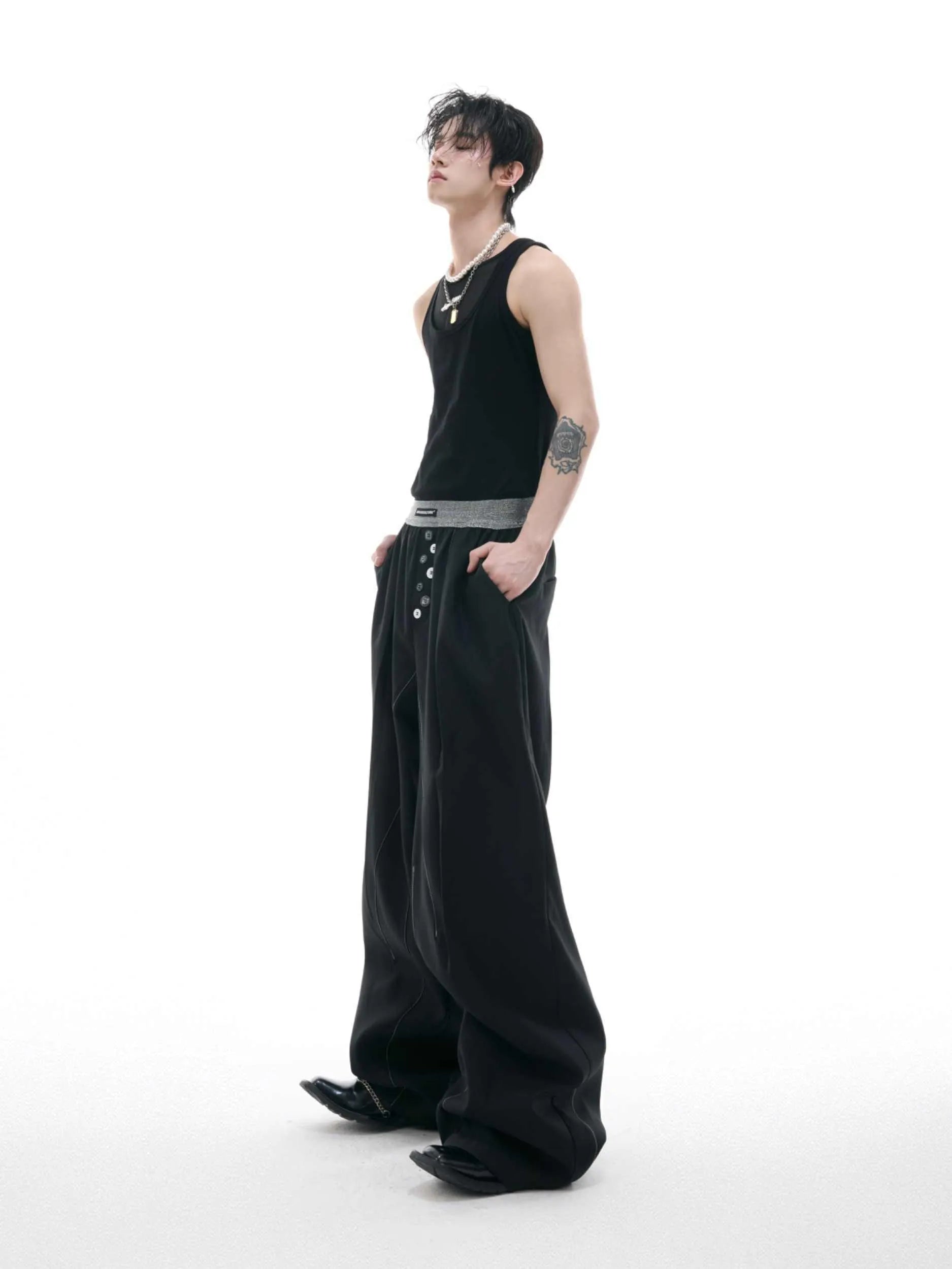 Straight-leg high-waisted trousers in grey fabric with button detail on the leg.