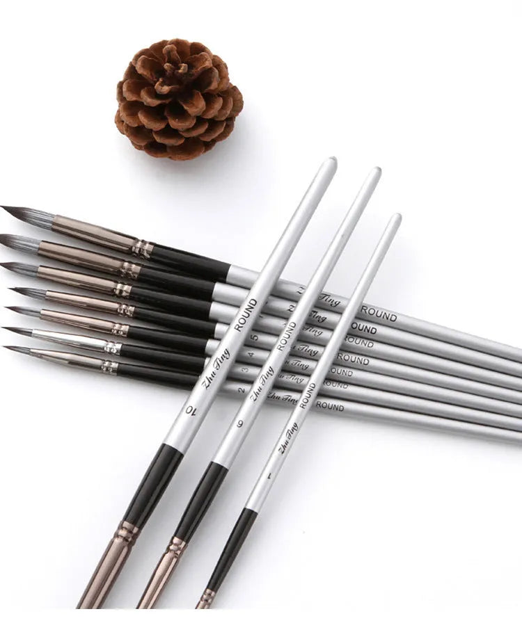 Ten black stick nylon paintbrushes with round tips, silver gray rods, and wood handles laid out