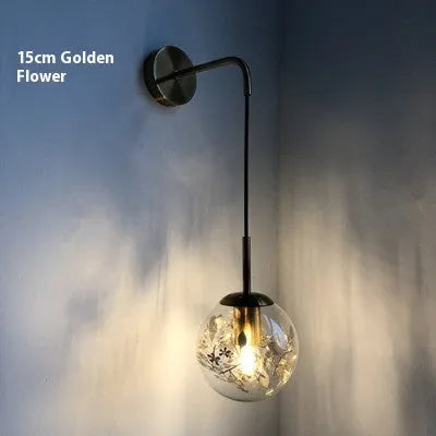 Modern creative wall-mounted bedside lamp with a golden flower glass shade and warm LED light.