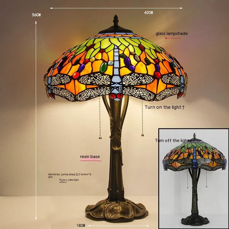 Tiffany-style stone table lamp with blue dragonfly design on a wooden surface.