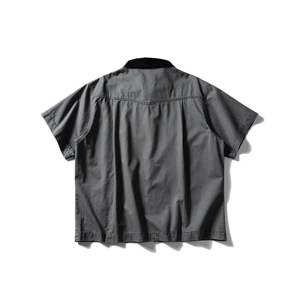 A khaki washed cotton overalls shirt with short sleeves and a loose cardigan style, laid flat.