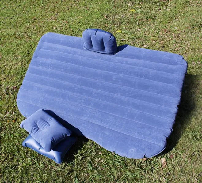 Inflatable car bed with flocking material shown in vehicle with two pillows and storage bag