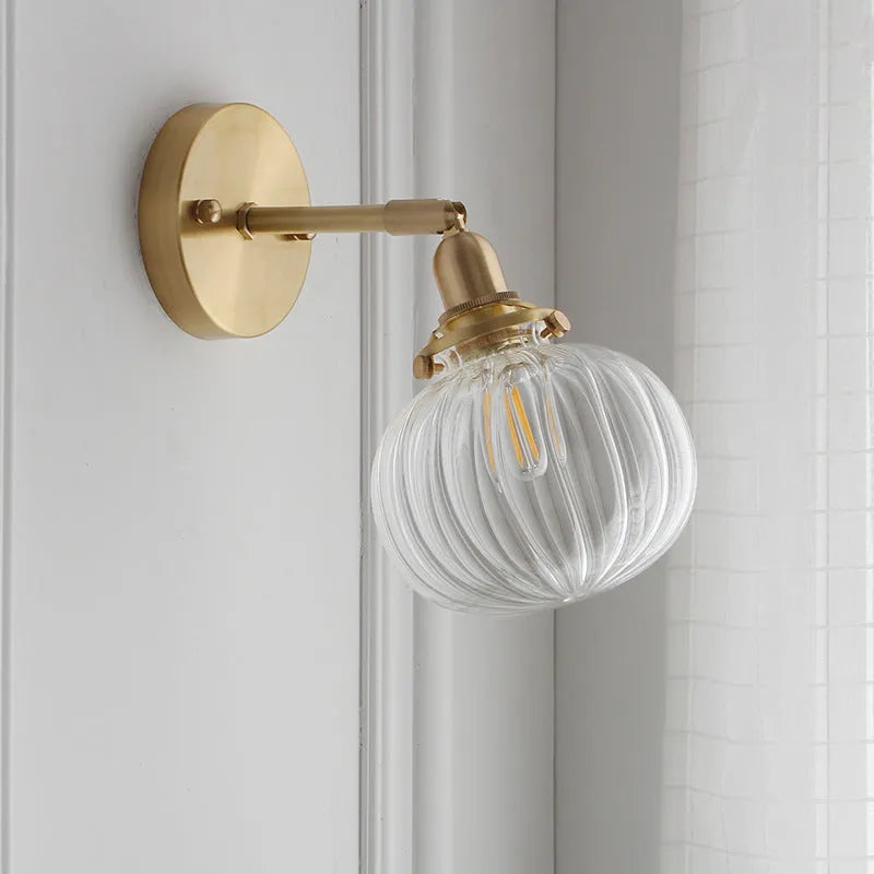 Close-up of a hand-blown water ripple glass wall lamp shade mounted on a white wall, showing its textured surface.
