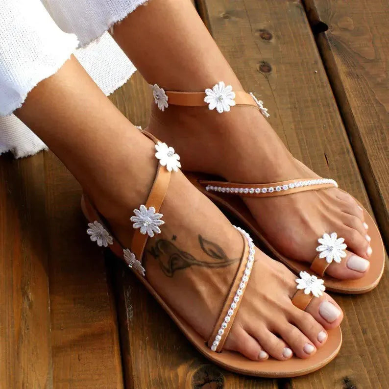 Brown ladies flat sandals with flower decoration and a rubber sole.