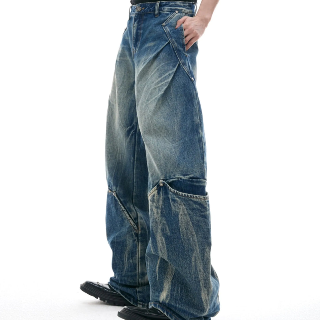 Man wearing verdant blue loose-fit retro jeans with a distinctive white burst pattern wash and a curved knife leg cut.