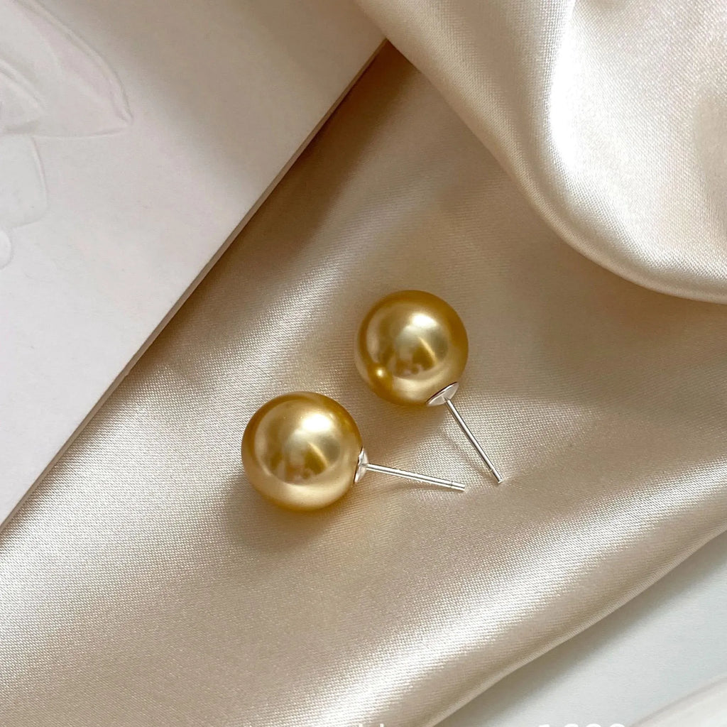 A pair of large pearl stud earrings with a geometric silver setting and an eight-pointed star detail on a white background.